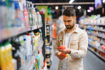 Man shopping for cleaning supplies in supermarket aisle