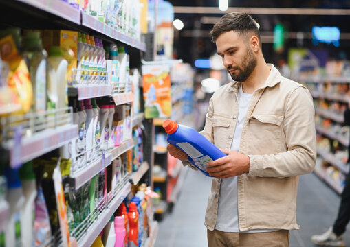 Man choosing detergent in supermarket cleaning aisle