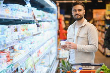 Man choosing dairy product in supermarket aisle