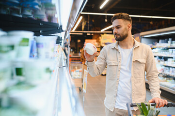 Man choosing dairy product in supermarket aisle