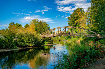 A lone kayaker on a river with a footbridge above