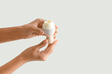 Female hands with boiled egg on white background