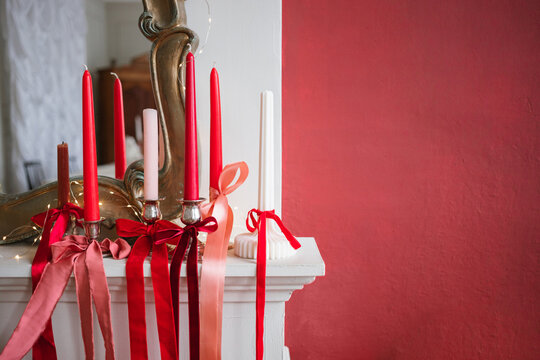 Close-up of ribbons tied around candlesticks on a fireplace with fairy lights