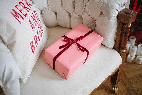 Overhead view of a wrapped gift on an armchair with a festive Christmas cushion