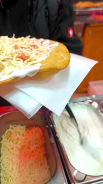 Cooking langos with salmon, cheese, and arugula at a street kitchen