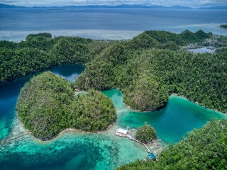 Floating pier and kayaks in turquoise lagoons surrounded by green islets © John