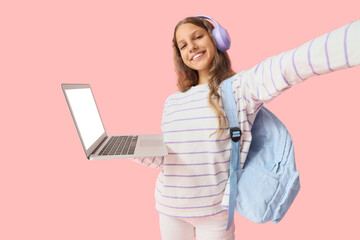 Female student in headphones with laptop taking selfie on pink background