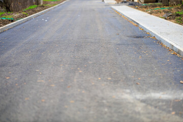Newly paved asphalt road with curb and minimal debris