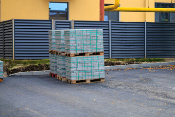 Pallets of concrete blocks or paving slabs at construction site on asphalt surface