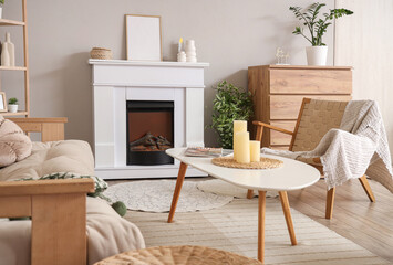 Fireplace, armchair and table in interior of light living room, closeup