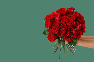 Female hands with bouquet of roses on green background. Valentine's Day celebration