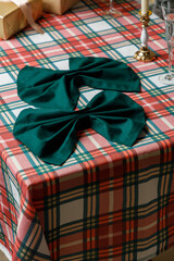 Green bow napkin on corner of plaid Christmas table
