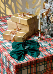 Gift boxes and green bow napkin on plaid table