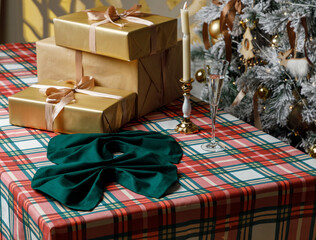 Gift boxes and green bow napkin on plaid Christmas table