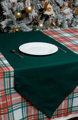 White plate on green runner over plaid holiday tablecloth
