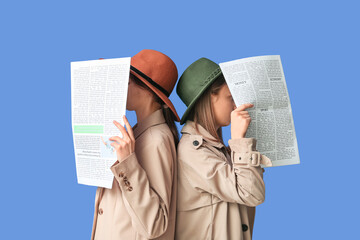 Women in cloak and hat with newspapers on blue background