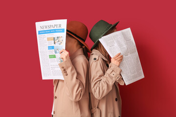 Women in cloak and hat with newspapers on red background