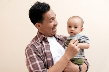 Southeast Asian dad with baby boy on his hands standing on white isolated background, Happiness of fatherhood. Loving father spending time with infant child. Fathers day concept.