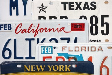 Old US car license plates with various state names close up. Concept of driving in United States. Reaching a car registration