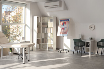 Interior of medical office with workplace, couch and shelf unit