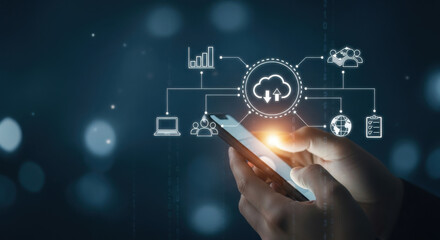 A smartphone displays illuminated cloud computing icons on a dark blue background, hands are interacting with the device highlighting technology and digital connectivity.