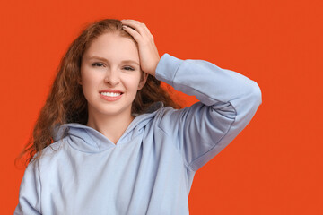 Portrait of ashamed young woman on red background