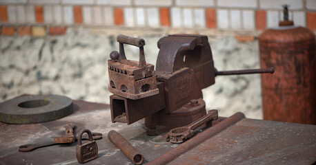 A cast iron iron and scattered tools.
A mechanic's workspace. Rare tools and household items. Rusty but essential items. Antiques.
