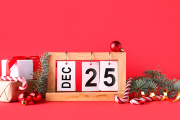 Gift boxes, decorations and calendar with date of Christmas on red background