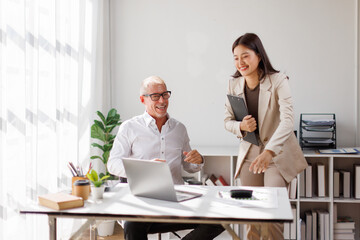 Team of happy business professionals engaged in a meeting, taking notes and collaborating in a sunlit office with lush indoor plants. Bright atmosphere and teamwork.
