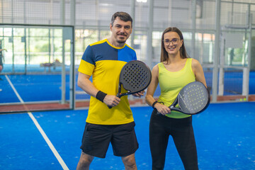 Padel couple. Family team mx. Group of two mix padel tennis players with racket. Woman and man athletes with paddle racket on the blue court. Sport concept.