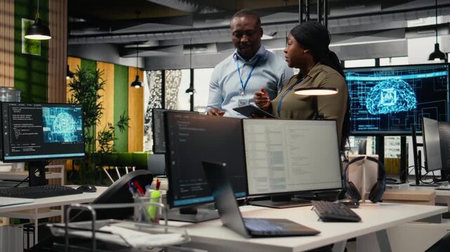Engineers in startup office work with artificial intelligence driving market innovation. African american tech agency coworkers apply machine learning to optimize operations and efficiency, camera A