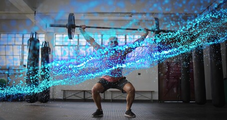 Lifting male athlete in dark red tee holding barbell overhead, squatting in gym with blue overlay