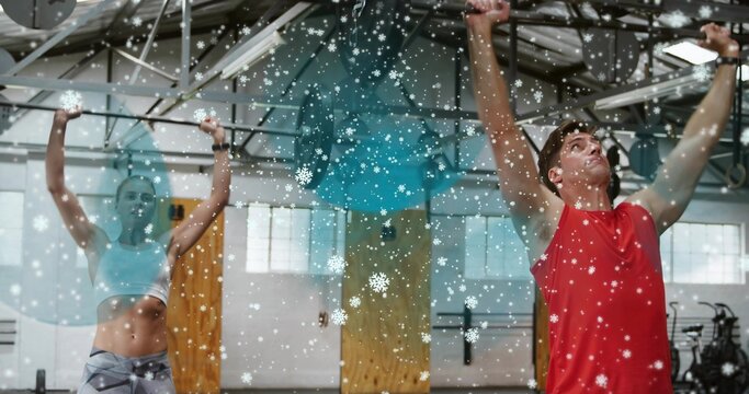Pulling man in red top on pull-up-rig in gym with woman wearing white-bra, snowflakes, copy space - Powered by Adobe
