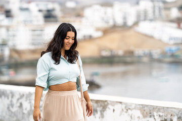 Young woman walking along coastal town feeling carefree