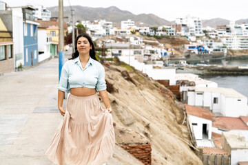 Young woman walking along coastal town path enjoying summer