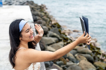 Young woman video calling by the sea