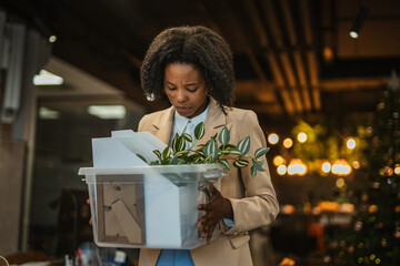 Businesswoman experiencing layoff, leaving office with personal belongings
