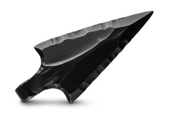 Sharply faceted obsidian projectile point rests on a white surface casting a subtle shadow