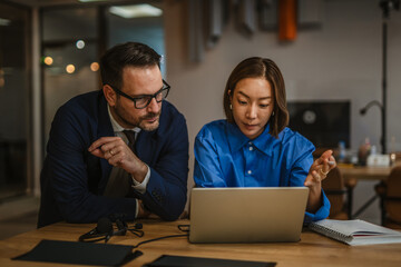 Business colleagues collaborating on laptop in modern office