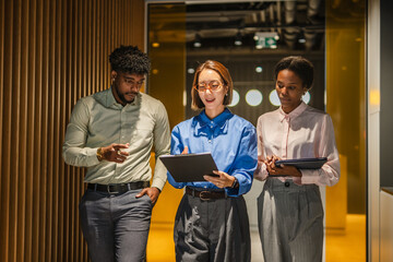 Diverse business people walking in office discussing project