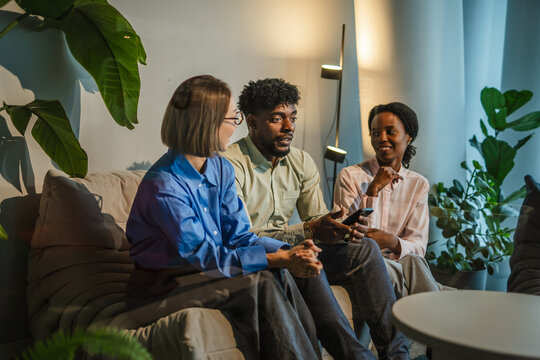 Diverse business people discussing and using smart phone in modern office - Powered by Adobe