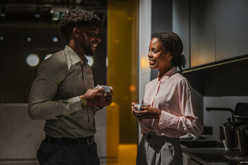 Colleagues having coffee break and casual conversation in office kitchen