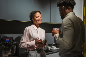 Colleagues having coffee break and casual conversation in office kitchen