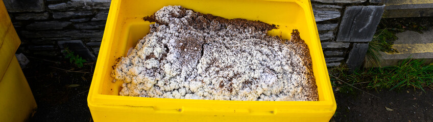 Bright yellow container of grit salt for icy or snow covered roadways to improve traction for safe travel, Isle of Skye, Scotland, UK
