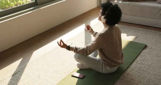 Prepping smartphone and headphones, man meditating focusing on breath on mat at home, copy space