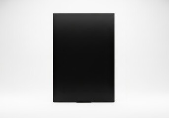Fototapeta premium Solid black vertical rectangular object stands centered against a plain bright background