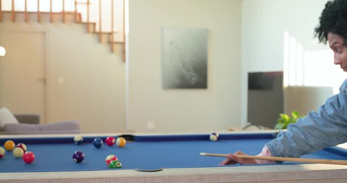 Man breaking rack, cue scattering balls, inspecting pool table for next shot at home, copy space