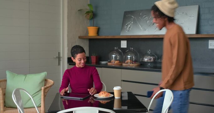Diverse couple meeting at cafe table, woman scrolling tablet, hugging  and  sharing coffee  and  pas