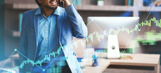 A middle eastern businessman is smiling while on the phone, discussing details in a contemporary office. He appears engaged with a digital graph overlay, indicating a business discussion.