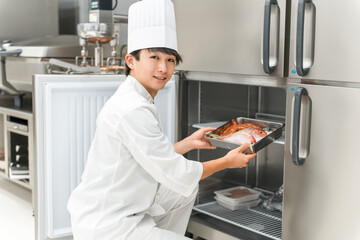 A male chef in a cook coat taking ingredients out of the refrigerator
